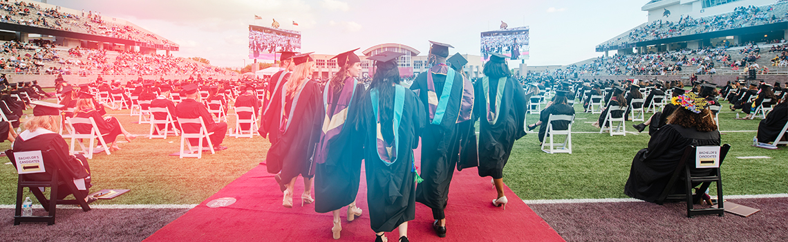 Students walking in graduation on the football field 